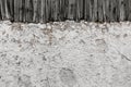 Closeup of snow-covered ground texture with old wooden fence on the background in a garden Royalty Free Stock Photo