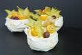 Closeup of snow-white Pavlova mini cakes with physalis and carambola