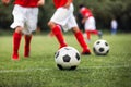 Closeup of soccer ball on grass pitch. Kid kicking classic black and white football balls on training Royalty Free Stock Photo