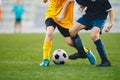 Closeup of soccer players legs in duel. Boys kicking football ball on grass venue