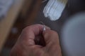 Closeup of someone picking on the bristles of a paintbrush with white dry paint on it