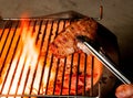 Closeup of someone turning a tasty steak cooking on a fire Royalty Free Stock Photo
