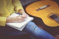 Closeup songwriter writing on note paper with acoustic guitar ne Royalty Free Stock Photo