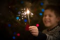 Closeup of a sparkler in hands of a happy kid boy. Christmas and Happy New Year celebration. Holidays season. Selective focus Royalty Free Stock Photo