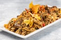 Closeup of spicy cooked rice with meat, vegetables and chips in a plate on the table Royalty Free Stock Photo