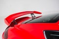 Closeup of a spoiler on a red modern car under the lights isolated on a grey background