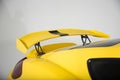Closeup of a spoiler on a yellow modern sports car under the lights isolated on a grey background