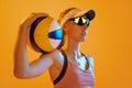 Closeup sportive young woman, beach volleyball player posing with ball  on orange color background. Sport Royalty Free Stock Photo