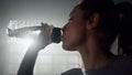 Girl drinking water from fitness bottle. Sportswoman standing in sport club Royalty Free Stock Photo