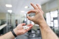 Closeup of sporty muscular man arms showing sports and fitness supplements, capsules, pills, gym background. Healthy lifestyle, Royalty Free Stock Photo