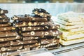 Closeup stack of assortment luxury handmade chocolate, dark and white chocolate bars with nuts in shop window.