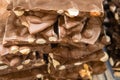 Closeup stack of assortment luxury handmade milk chocolate bars with nuts in shop window. Selective focus. Sweet
