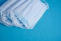 Closeup of a stack of face masks under the lights on a blue table - COVID-19 Royalty Free Stock Photo