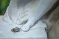 A stack of four Russian coins lying next to the feet of an antique marble statue with a blurred background