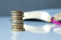 A closeup of a stack of golden coins with a Holy Bible Book in the background Royalty Free Stock Photo