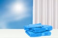 Closeup of a stack or pile of blue soft terry bath towels on a bright table over abstract blurred natural blue sky background with Royalty Free Stock Photo