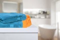 Closeup of a stack or pile of blue and a yellow soft terry bath towels on a table over blurred bathroom background with copy space Royalty Free Stock Photo