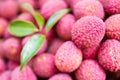 Closeup of stack of pink Lychee fruits and green leaves