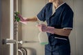 Close up of chambermaid wearing uniform and gloves cleaning elevator with detergent and rag Royalty Free Stock Photo