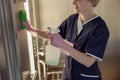 Close up of chambermaid wearing uniform and gloves cleaning elevator with detergent and rag Royalty Free Stock Photo