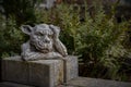 Closeup of a statue of a gargoyle or a gordon with its hand on the head in a park or garden Royalty Free Stock Photo