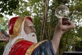 Closeup of a Statue of a wizard holding a glass bowl in his hand, in a theme park, France