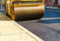 Steamroller compacting asphalt in road repaving project.