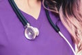 Closeup of a stethoscope on a female nurse in a purple uniform