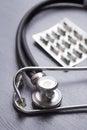 Closeup stethoscope with capsules in blister pack on gray table