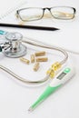 Closeup a stethoscope, thermometer, pills, notepad, pen and glasses on doctor table Royalty Free Stock Photo