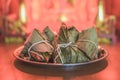 Closeup Sticky rice dumpling or Zongzi on stainless steel tray in front of Chinese spirit`s house during Dragon Boat Festival. Royalty Free Stock Photo