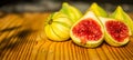 Closeup still life of group of whole panachee variegated striped figs on brown wooden cutting board with one fig sliced in half in