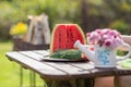 Closeup still life watermelon on brown wooden table with bokeh nature on background. Flowers in a small ceramic watering can Royalty Free Stock Photo