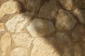 Closeup of a stone beige wall in shadows