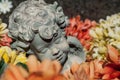 stoned angel sleeping in colorful flowers on tomb at