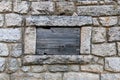 Closeup of a stonewall background with a small wooden window cover Royalty Free Stock Photo