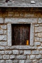 Closeup of a stonewall background with a small wooden window cover Royalty Free Stock Photo