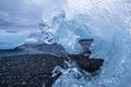 Closeup of a stranded iceberg in the shape of a frozen wave during midnight sun on a cloudy night at the black deamond beach in I