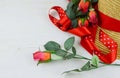 Closeup of a straw hat being decorated with red ribbons and roses on a white washed rustic wooden background Royalty Free Stock Photo