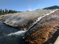 Closeup of stream of steaming water flowing into river at Yellowstone National Park