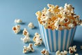 closeup striped paper box filled with delicious popcorn on a blue background