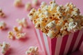 closeup striped paper box filled with delicious popcorn on a pink background