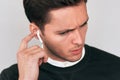 Closeup studio portrait of sad young Caucasian handsome man speaking with a friend using wireless earphones. Royalty Free Stock Photo