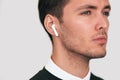 Closeup studio portrait of serious young handsome man posing with wireless earphones on white studio background. Royalty Free Stock Photo