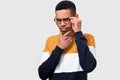 Closeup studio portrait of young African American man wearing and looking through round trendy spectacles. Serious businessman