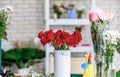 Closeup studio shot fresh red and pink petal roses bunch bouquet in white ceramic vase placed on workshop table with other Royalty Free Stock Photo