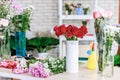 Closeup studio shot fresh red and pink petal roses bunch bouquet in white ceramic vase placed on workshop table with other Royalty Free Stock Photo