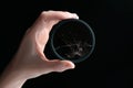 Closeup studio shot of hand holding black circular polarizer filter with cracked glass, isolated on black background