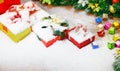 Closeup studio shot of Red paper wrapped present gift boxes with gold ribbon bowtie covered by white snow placed on wood table Royalty Free Stock Photo