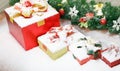 Closeup studio shot of Red paper wrapped present gift boxes with gold ribbon bowtie covered by white snow placed on wood table Royalty Free Stock Photo